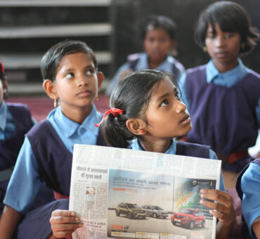 Schoolchildren in classroom reading a newspaper