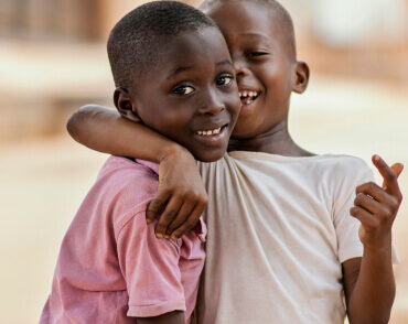 Two smiling children hugging outdoors